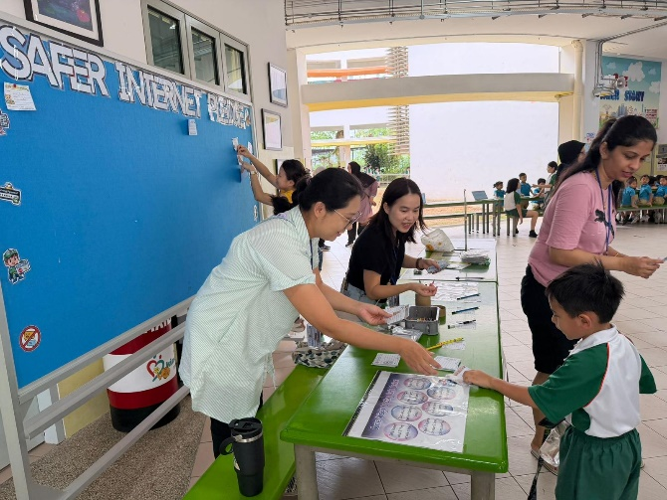 Student signing a safer internet pledge at a school cyber wellness booth.